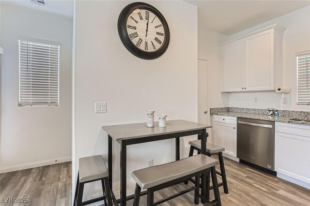 1611 Prairie Fields Ct, Las Vegas, NV 89115 - kitchen with stainless steel dishwasher, light wood-style flooring, white cabinetry, and light stone countertops