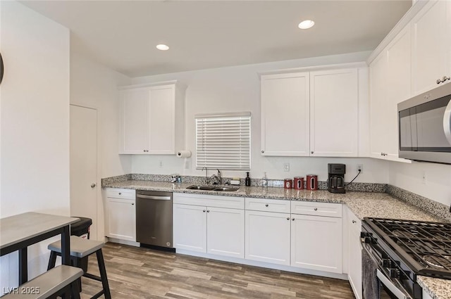 1611 Prairie Fields Ct, Las Vegas, NV 89115 - kitchen with stainless steel appliances, white cabinetry, recessed lighting, light wood-type flooring, and light stone counters