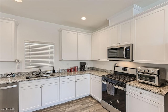 1611 Prairie Fields Ct, Las Vegas, NV 89115 - kitchen featuring stainless steel appliances, a sink, white cabinetry, recessed lighting, and light wood finished floors