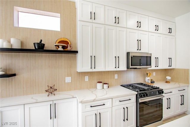 9813 Folsom Dr, Las Vegas, NV 89134 - kitchen with gas range, stainless steel microwave, white cabinetry, light stone counters, and open shelves