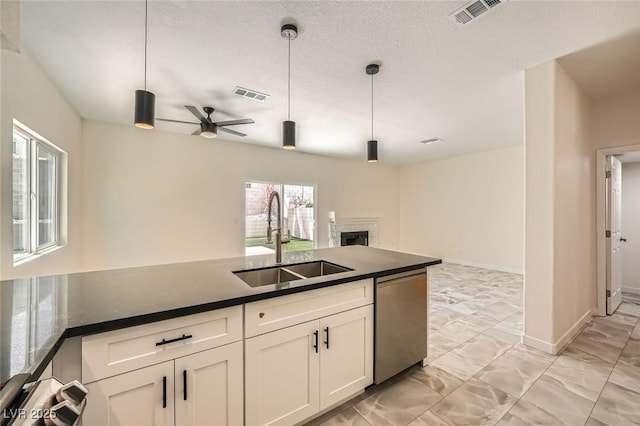 1501 Lucia Dr, Las Vegas, NV 89128 - kitchen with stainless steel dishwasher, open floor plan, dark countertops, a fireplace, and white cabinetry