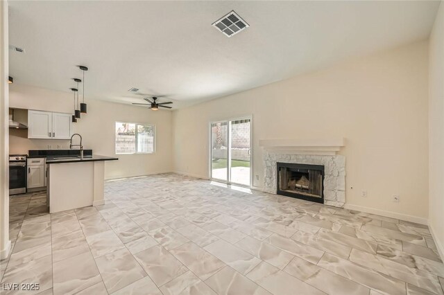 1501 Lucia Dr, Las Vegas, NV 89128 - unfurnished living room with a ceiling fan, a stone fireplace, and light marble finish flooring