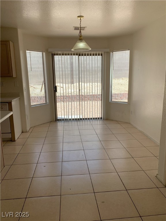6470 Shining Sand Ave, Las Vegas, NV 89142 - unfurnished dining area with light tile patterned flooring and a textured ceiling
