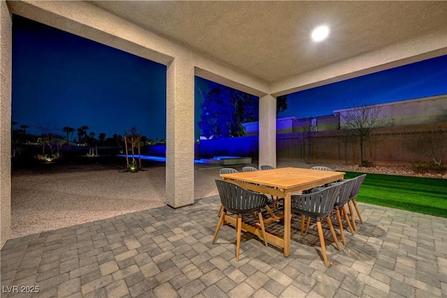 7736 Tioga Ridge Ct, Las Vegas, NV 89117 - patio at night with a patio, a fenced backyard, a swimming pool, and outdoor dining area