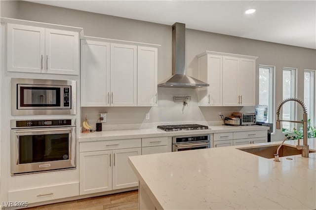 7736 Tioga Ridge Ct, Las Vegas, NV 89117 - kitchen featuring stainless steel appliances, wall chimney range hood, white cabinetry, light stone countertops, and recessed lighting