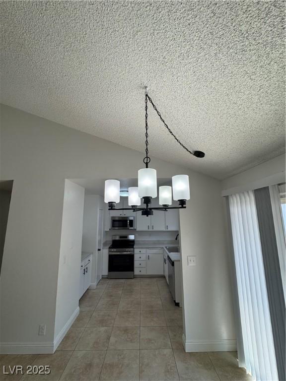 2318 El Molino Cir, Las Vegas, NV 89108 - kitchen featuring stainless steel appliances, a textured ceiling, vaulted ceiling, white cabinetry, and light countertops