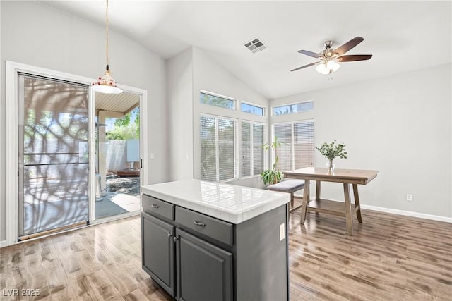 981 Leadville Meadows Dr, Henderson, NV 89052 - kitchen featuring light wood finished floors, ceiling fan, healthy amount of natural light, gray cabinets, and high vaulted ceiling