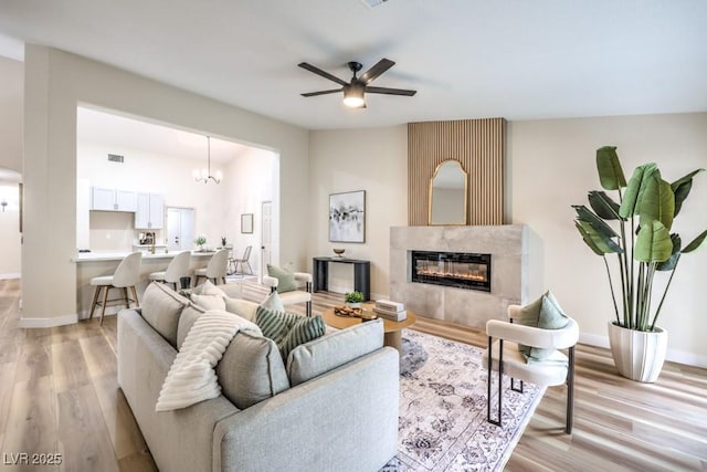 10205 Birch Bluff Ln, Las Vegas, NV 89145 - living room with light wood-style flooring, a ceiling fan, a high end fireplace, and a chandelier
