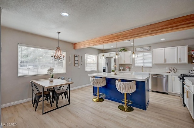 700 Cactus Ln, Las Vegas, NV 89107 - kitchen with appliances with stainless steel finishes, light wood-style floors, beamed ceiling, a textured ceiling, and a center island
