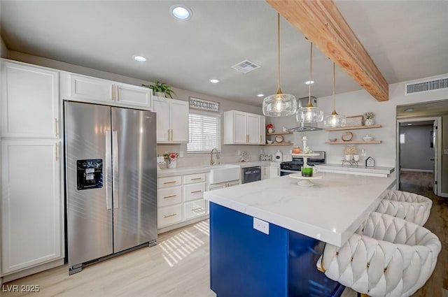 700 Cactus Ln, Las Vegas, NV 89107 - kitchen with appliances with stainless steel finishes, open shelves, light wood-style flooring, white cabinets, and a breakfast bar area