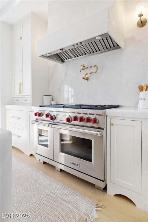 1990 Country Cove Ct, Las Vegas, NV 89135 - kitchen with range with two ovens, custom exhaust hood, white cabinetry, backsplash, and light countertops
