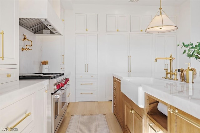 1990 Country Cove Ct, Las Vegas, NV 89135 - kitchen with range with two ovens, custom range hood, light countertops, white cabinetry, and light wood-style flooring