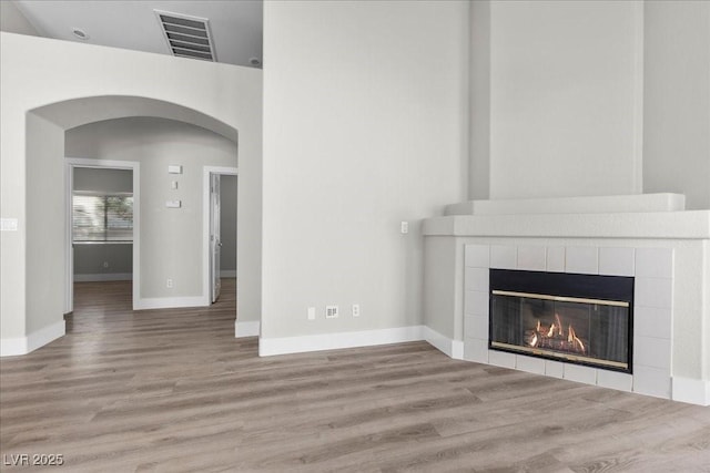 10613 Tiffanieville Ct, Las Vegas, NV 89129 - unfurnished living room featuring arched walkways, wood finished floors, and a tile fireplace