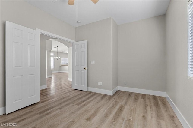 10613 Tiffanieville Ct, Las Vegas, NV 89129 - empty room with arched walkways, light wood-style flooring, a ceiling fan, and a chandelier