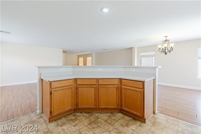 11577 Vesuvio Ct, Las Vegas, NV 89183 - kitchen with light countertops, a chandelier, brown cabinetry, light wood finished floors, and recessed lighting