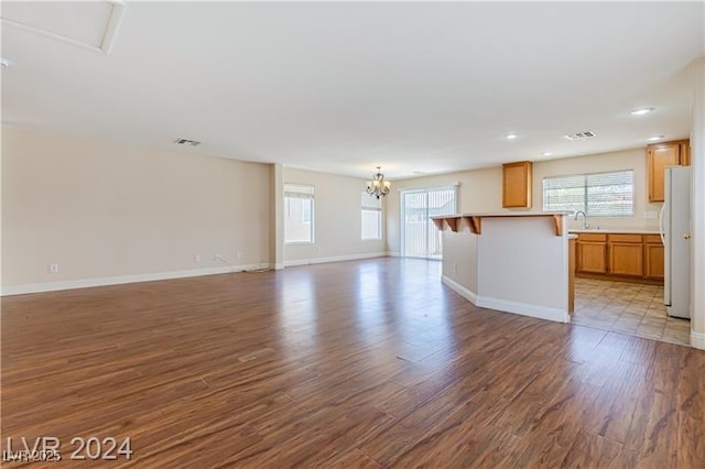 11577 Vesuvio Ct, Las Vegas, NV 89183 - unfurnished living room featuring wood finished floors, a chandelier, healthy amount of natural light, and recessed lighting