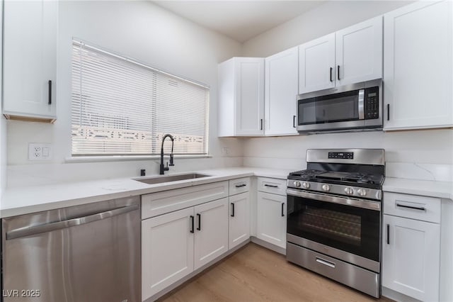 3915 Delling Ct, Las Vegas, NV 89104 - kitchen with stainless steel appliances, white cabinetry, light wood finished floors, and light stone counters