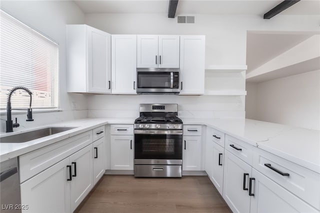 3915 Delling Ct, Las Vegas, NV 89104 - kitchen featuring appliances with stainless steel finishes, open shelves, white cabinetry, beam ceiling, and light stone countertops