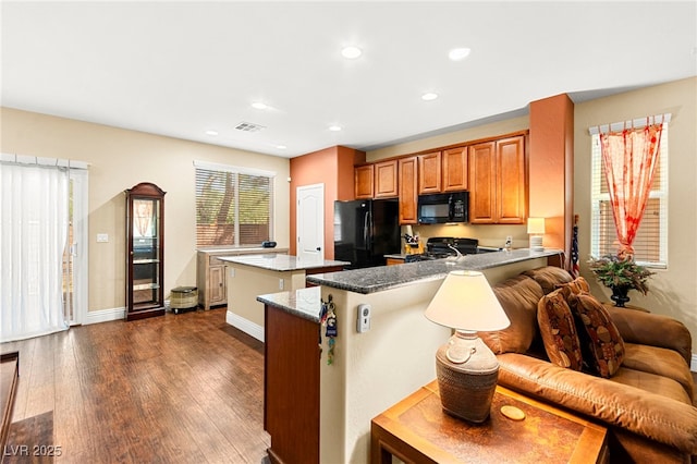 8316 Mokena Ave, Las Vegas, NV 89178 - kitchen with black appliances, a kitchen island, brown cabinets, dark wood-style flooring, and a peninsula