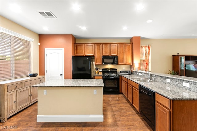 8316 Mokena Ave, Las Vegas, NV 89178 - kitchen featuring black appliances, dark wood-style flooring, a peninsula, a center island, and light stone countertops