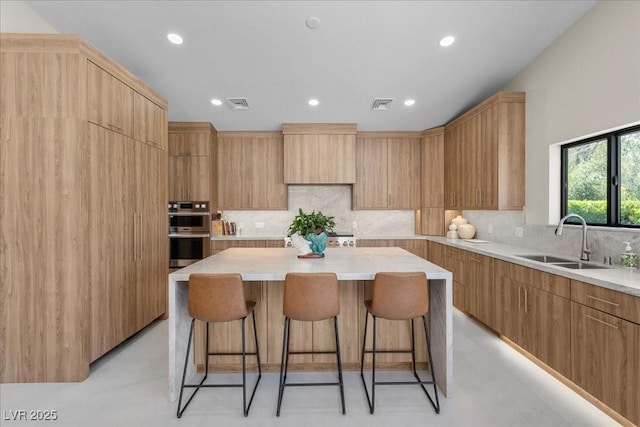 3104 Conners Dr, Las Vegas, NV 89107 - kitchen featuring stainless steel double oven, a center island, a kitchen bar, decorative backsplash, and recessed lighting