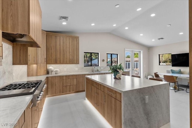 3104 Conners Dr, Las Vegas, NV 89107 - kitchen featuring stainless steel gas cooktop, modern cabinets, a kitchen island, lofted ceiling, and decorative backsplash