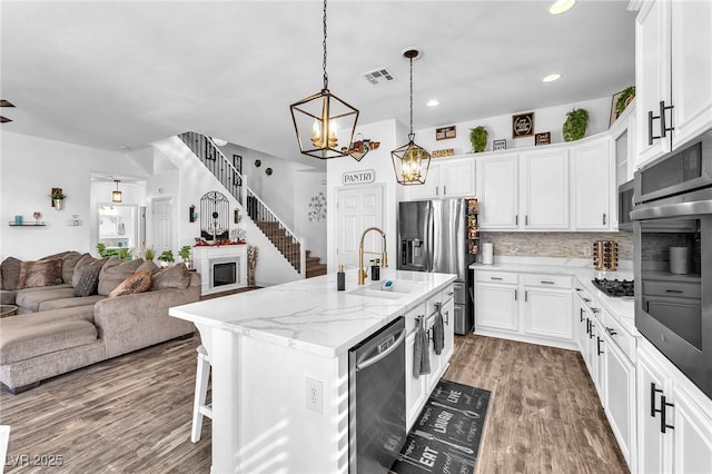 10654 Sidlaw Hills Ct, Las Vegas, NV 89141 - kitchen featuring appliances with stainless steel finishes, open floor plan, wood finished floors, white cabinetry, and recessed lighting