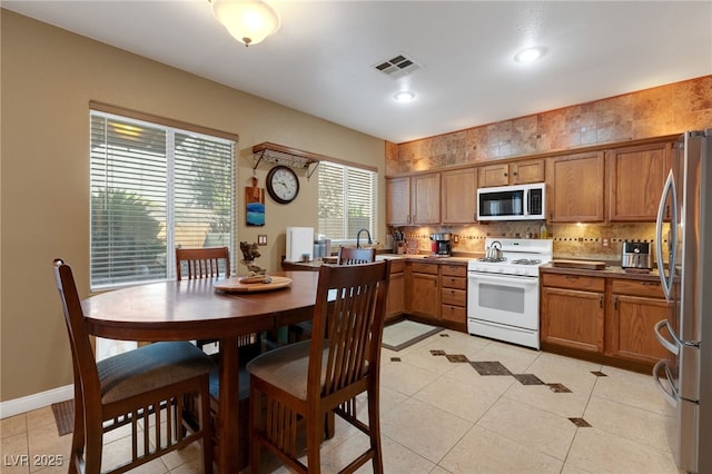 4415 Peaceful Harbor St, Las Vegas, NV 89129 - kitchen with white appliances, brown cabinetry, decorative backsplash, light tile patterned floors, and recessed lighting