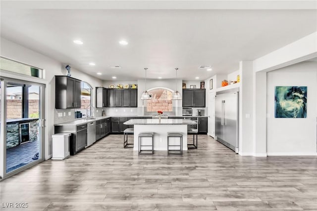 5976 Rockway Glen Ave, Las Vegas, NV 89141 - kitchen with appliances with stainless steel finishes, light countertops, light wood finished floors, a center island, and recessed lighting
