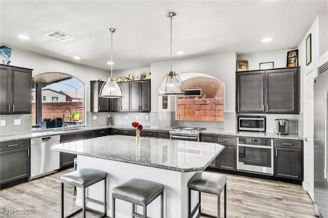 5976 Rockway Glen Ave, Las Vegas, NV 89141 - kitchen with appliances with stainless steel finishes, a breakfast bar, light wood finished floors, tasteful backsplash, and recessed lighting