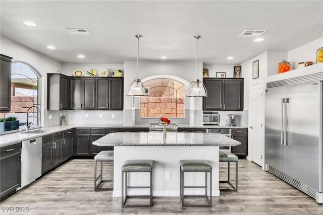 5976 Rockway Glen Ave, Las Vegas, NV 89141 - kitchen with appliances with stainless steel finishes, a breakfast bar area, light stone countertops, a center island, and recessed lighting