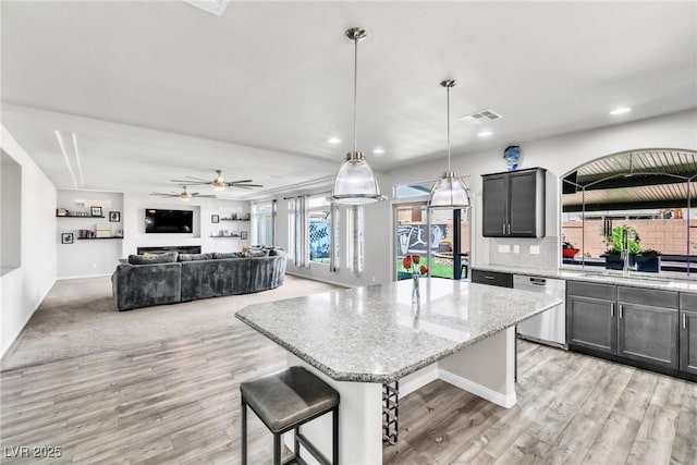 5976 Rockway Glen Ave, Las Vegas, NV 89141 - kitchen featuring stainless steel dishwasher, a center island, light wood-type flooring, light stone countertops, and decorative backsplash