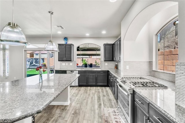 5976 Rockway Glen Ave, Las Vegas, NV 89141 - kitchen featuring stainless steel appliances, light stone counters, tasteful backsplash, light wood finished floors, and pendant lighting