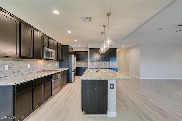 6085 Ryan Ranch Ave, Las Vegas, NV 89130 - kitchen featuring appliances with stainless steel finishes, backsplash, light stone countertops, recessed lighting, and light wood finished floors
