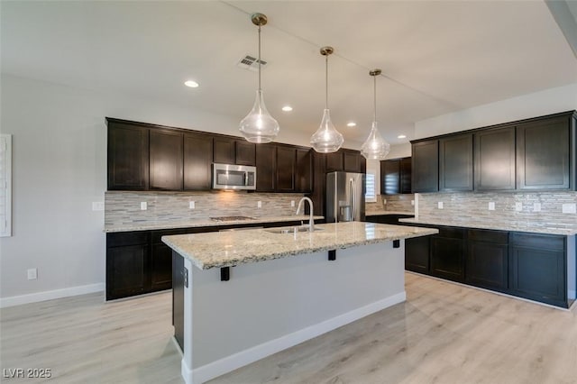 6085 Ryan Ranch Ave, Las Vegas, NV 89130 - kitchen with stainless steel appliances, light wood-style floors, backsplash, a kitchen bar, and light stone counters