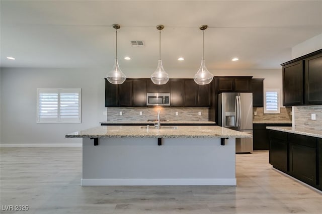 6085 Ryan Ranch Ave, Las Vegas, NV 89130 - kitchen with appliances with stainless steel finishes, a breakfast bar, decorative backsplash, light stone countertops, and recessed lighting