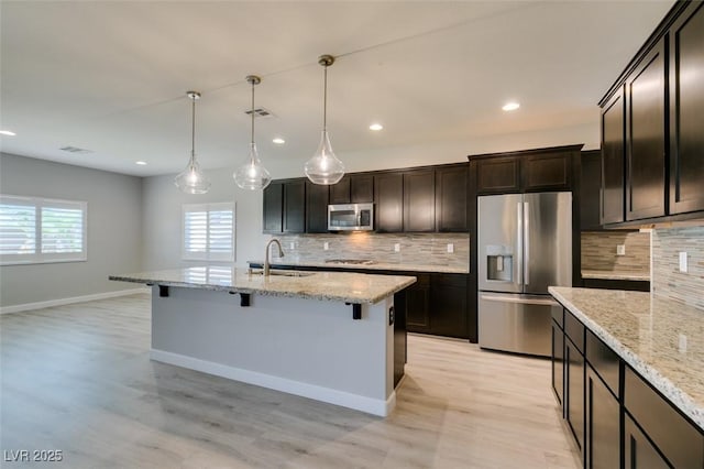 6085 Ryan Ranch Ave, Las Vegas, NV 89130 - kitchen with stainless steel appliances, a breakfast bar area, recessed lighting, decorative backsplash, and light wood-type flooring