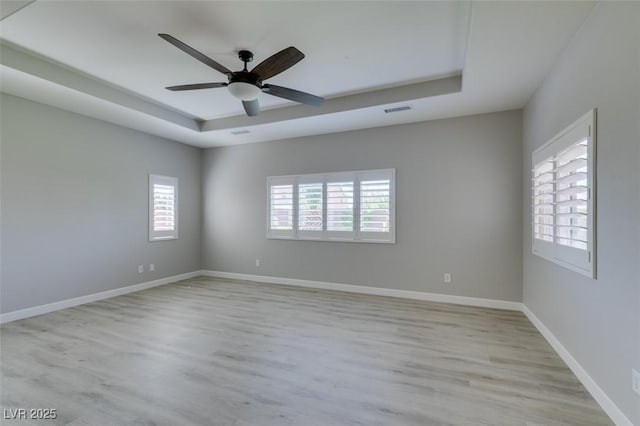 6085 Ryan Ranch Ave, Las Vegas, NV 89130 - spare room featuring a tray ceiling, healthy amount of natural light, and light wood finished floors