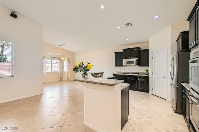 9252 Oxbow Lake Ave, Las Vegas, NV 89149 - kitchen with stainless steel appliances, dark cabinetry, light tile patterned floors, light stone countertops, and lofted ceiling