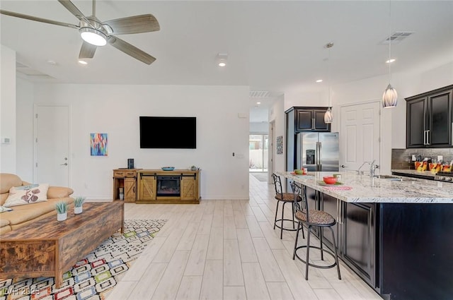 794 Sunny Sagebrush St, Henderson, NV 89011 - kitchen featuring stainless steel refrigerator with ice dispenser, open floor plan, a breakfast bar, light stone counters, and backsplash