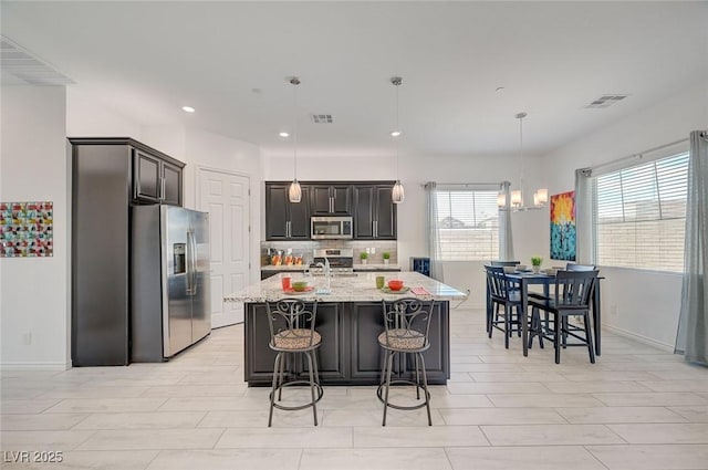 794 Sunny Sagebrush St, Henderson, NV 89011 - kitchen with appliances with stainless steel finishes, recessed lighting, light stone countertops, decorative backsplash, and an island with sink