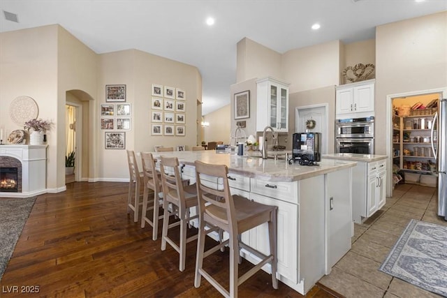 10638 La Spezia Way, Las Vegas, NV 89141 - kitchen featuring arched walkways, appliances with stainless steel finishes, a large island with sink, white cabinetry, and a kitchen breakfast bar