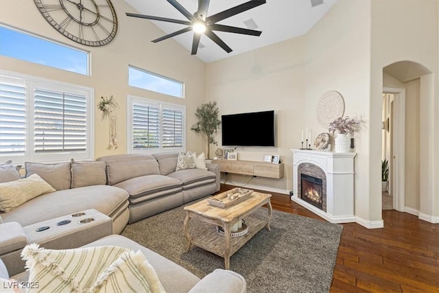 10638 La Spezia Way, Las Vegas, NV 89141 - living area featuring high vaulted ceiling, ceiling fan, arched walkways, hardwood / wood-style flooring, and a warm lit fireplace