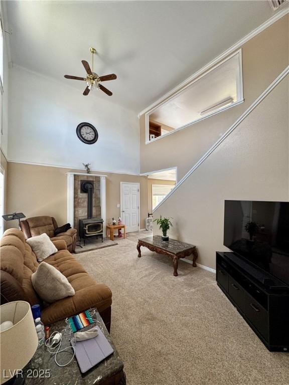 2345 Iron Dr, Ely, NV 89301 - carpeted living room with a wood stove, ceiling fan, a towering ceiling, and plenty of natural light