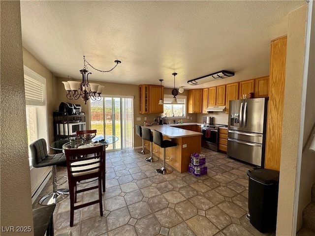 2345 Iron Dr, Ely, NV 89301 - kitchen featuring appliances with stainless steel finishes, a peninsula, glass insert cabinets, a kitchen breakfast bar, and brown cabinetry