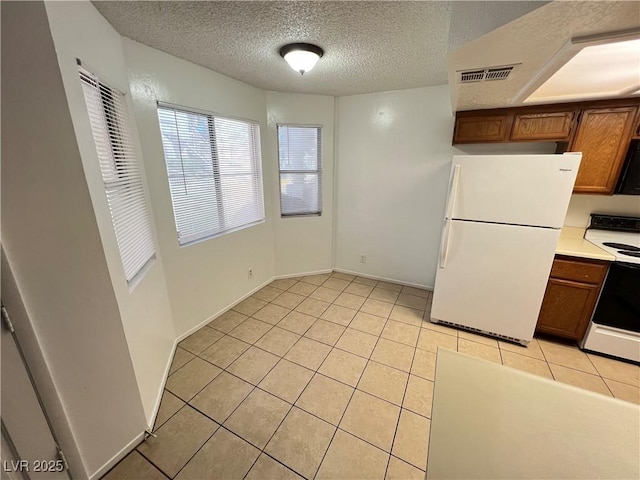 7948 Calico Vista Blvd Unit 101, Las Vegas, NV 89128 - kitchen with white appliances, light tile patterned floors, a textured ceiling, light countertops, and brown cabinets