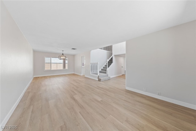 1511 Irene Dr, Boulder City, NV 89005 - unfurnished living room with a chandelier, light wood-style floors, and stairs