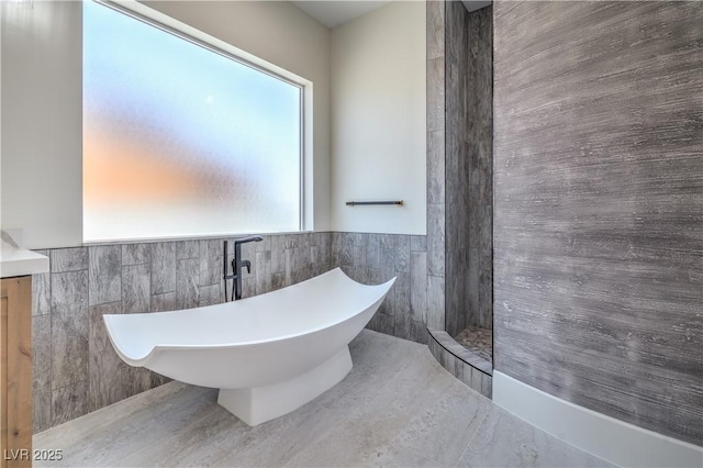 1525 Heights Dr, Logandale, NV 89021 - bathroom with a freestanding bath, tile walls, vanity, walk in shower, and a wainscoted wall