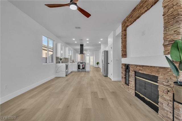 10200 Wood Work Ln, Las Vegas, NV 89135 - unfurnished living room featuring ceiling fan, a stone fireplace, light wood finished floors, and recessed lighting