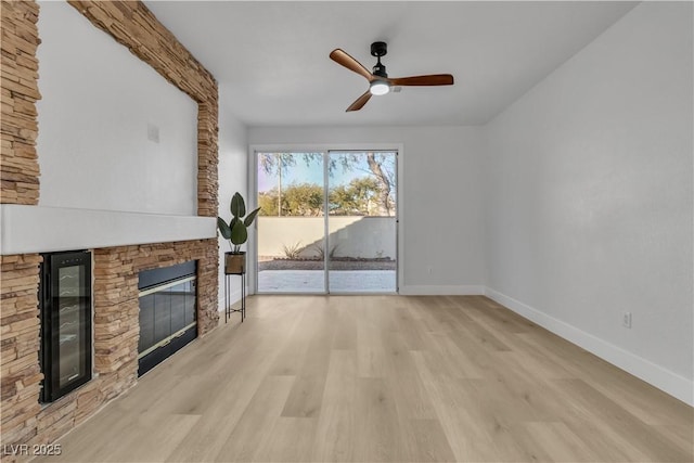 10200 Wood Work Ln, Las Vegas, NV 89135 - unfurnished living room featuring beverage cooler, a stone fireplace, wood finished floors, and ceiling fan